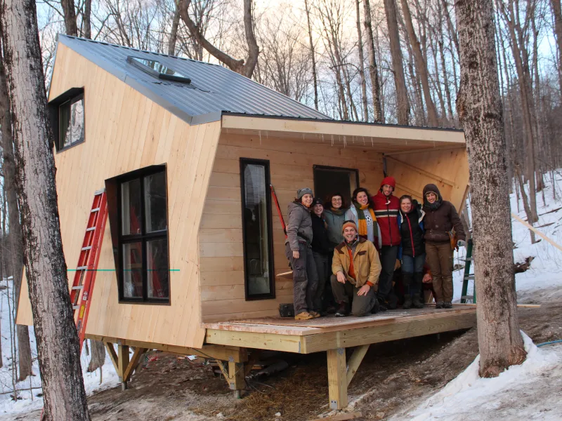 Small, newly built ADU Cabin in the woods, with a class of young builders on the deck.