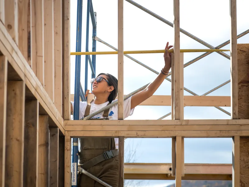 A student uses a measuring tape on a framed wall