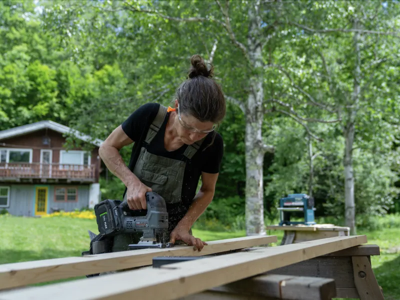 A carpentry student uses a circular saw to cut a piece of lumber.