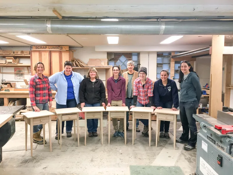 A group of students poses for a class photo with their end tables.