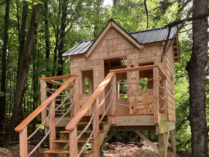 A shingled playstructure in the woods