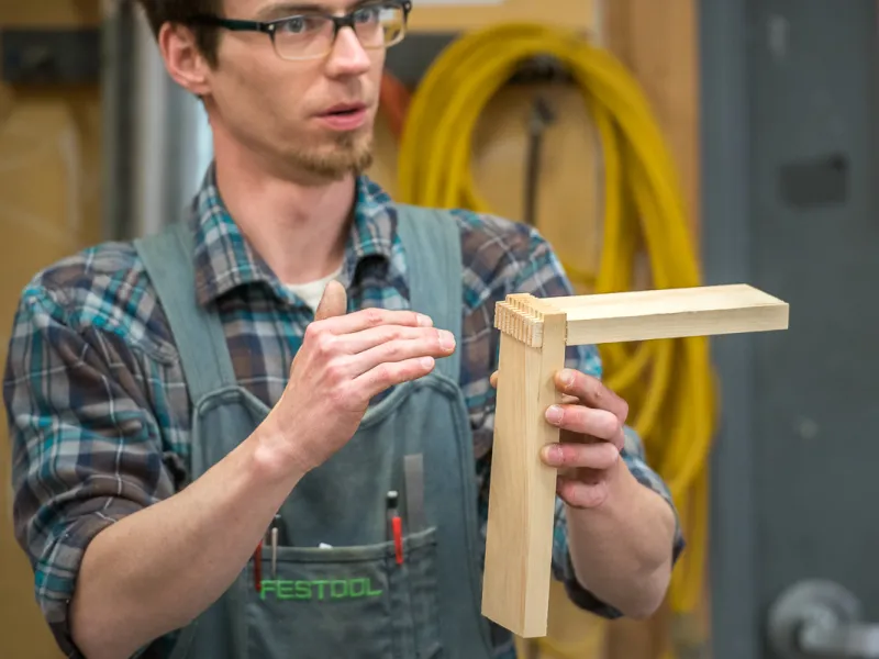 A photo of an instructor demonstrating dovetail joinery. 