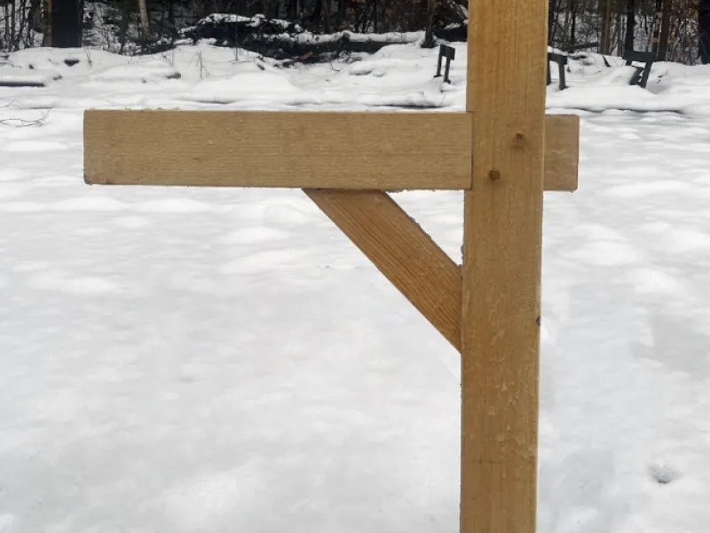 A wooden mailbox post in a snowy field. 