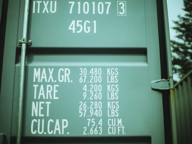 The door of a green shipping container with shipping code information written in white letters