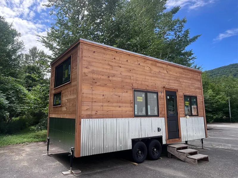 A tiny house on wheels with pine board siding.
