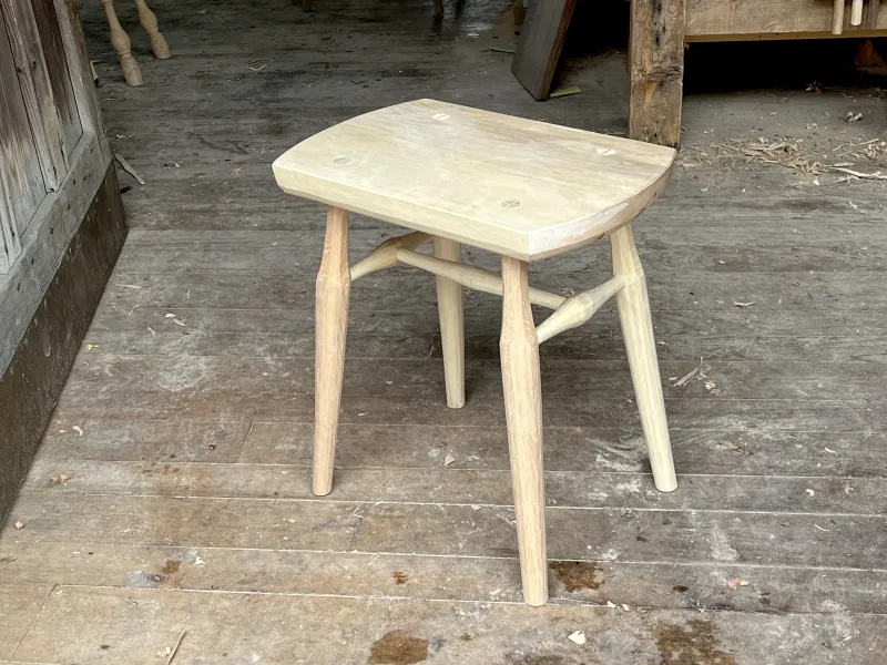 A rustic wooden stool with four legs. 