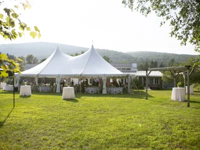 Image of the Yestermorrow lawn in Summer, with white celebration tent and main building in the background