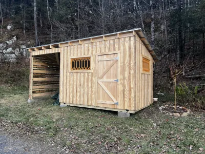 A wooden shed with unique orange windows and an overhang for outdoor storage.