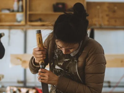 A students uses a chisel to cut a mortise in a beam