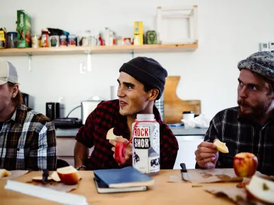 A few students sit in a classroom eating apples.