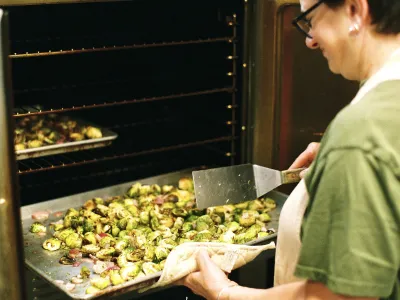 Chef Michelle puts a tray of brussels sprouts in the oven.