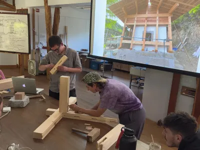 Students use demo joints in the main studio with a presentation screen in the background showing Japanese carpentry.