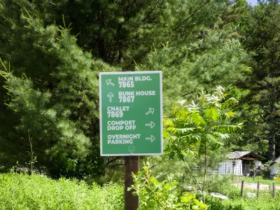 A green wayfinding sign stands outside in a garden bed.