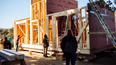 Wide shot of a partially framed building with students in the foreground.