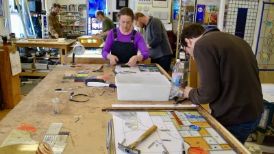 Students at a workbench assemble stained glass pieces.