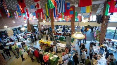Shot from above of an exhibition hall with flags of the world in the foreground hanging from the ceiling