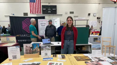 Sarah smiles behind the Yestermorrow table set up at the LEAP energy fair