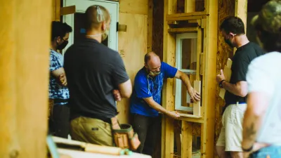 A person demonstrates on a trimmed window opening inside a framed structure.