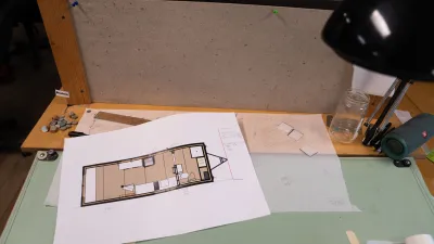 A sketchup model of a tiny house lies on a drafting table