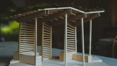 A wooden model of a bus stop structure featuring benches and wood slates designed by students in 2019.