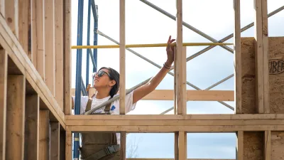 A student uses a measuring tape on a framed wall