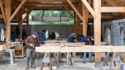 Students work on cutting joinery on timbers in an outdoor classroom