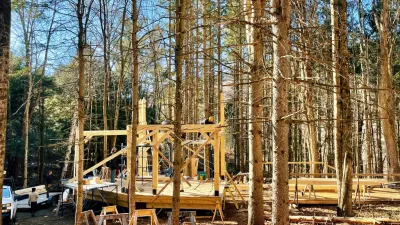 Wide shot of a timber frame under construction in the forest.