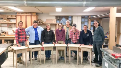 A group of students poses for a class photo with their end tables.