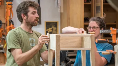 Two people work on a side table in the woodshop.