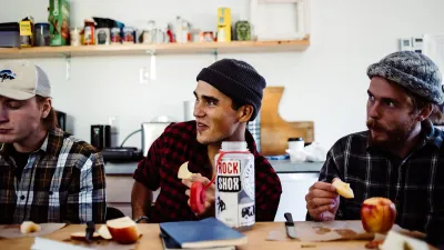 A few students sit in a classroom eating apples.