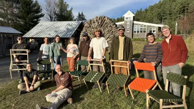 A group of students poses outside with the chairs they made.