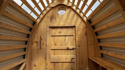 The interior of a project completed by the 2024 Collaborative Design/Build Intensive featuring wood siding, a curved roof and clear roof panels.