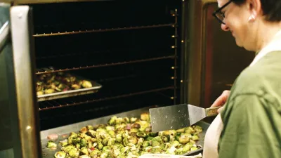 Chef Michelle puts a tray of brussels sprouts in the oven.