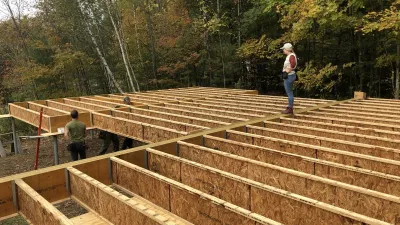 A floor deck is being framed with joists exposed and trees in the background.