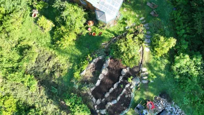 Aerial view of a home with a garden patch and lawn