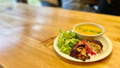plate of food on wood table in the foreground, students eating at a table in the background