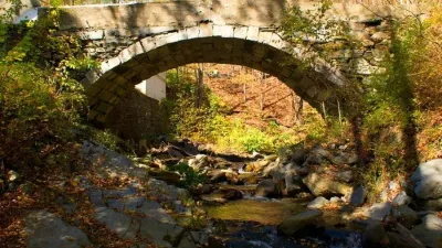 The Townshend stone arch bridge is photographed in the Fall with foliage.