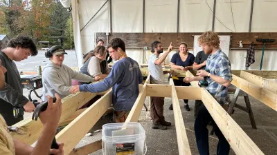 2026 Semester students gather around their floor deck in the outdoor hangar, working to finish up the framing.