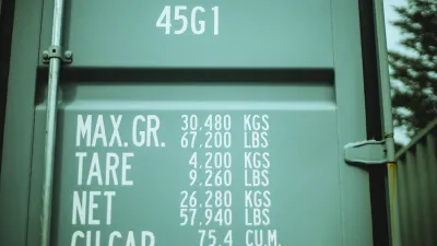 The door of a green shipping container with shipping code information written in white letters