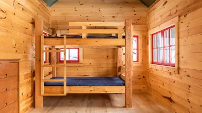 Interior shot of the slate cabin with wood paneling inside and two bunk beds.