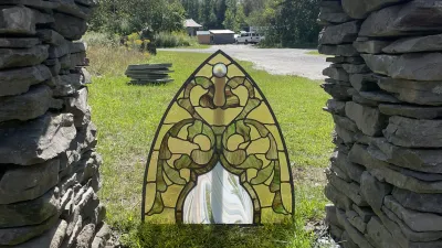 A stained glass panel in an arch shape is pictured outside.