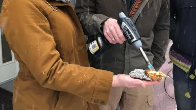 A student holds a piece of insulation while an instructor torches it, without hurting the student's hand (the student looks surprised and delighted)