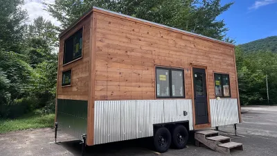A tiny house on wheels with pine board siding.