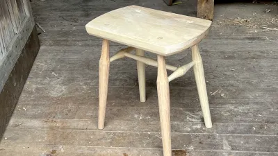 A rustic wooden stool with four legs. 