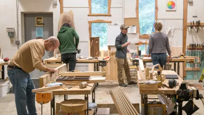 Several people are pictured in a wide shot of the woodshop. 