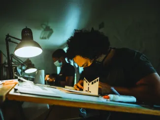 Students make models at drafting tables in the main studio