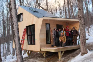 Small, newly built ADU Cabin in the woods, with a class of young builders on the deck.