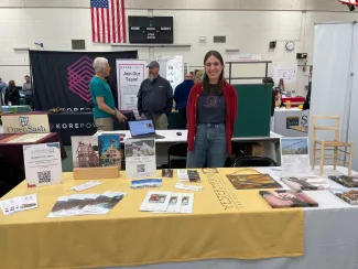 Sarah smiles behind the Yestermorrow table set up at the LEAP energy fair