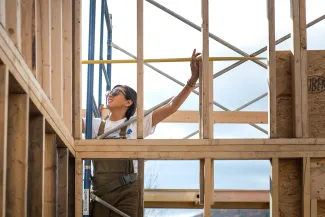 A student uses a measuring tape on a framed wall