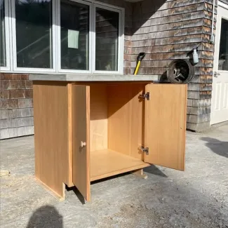 A douglas fir wood bathroom vanity cabinet with the doors open to show the inside.  